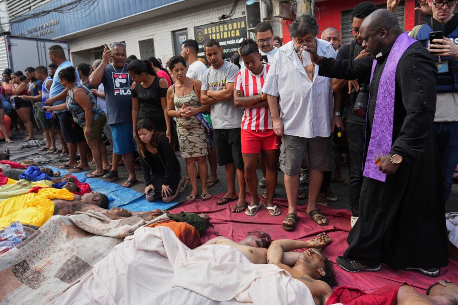 FILE - A priest blesses the bodies of people killed the day before during a police raid targeting the Comando Vermelho gang in the Complexo da Penha favela of Rio de Janeiro, Brazil, Wednesday, Oct. 29, 2025. (AP Photo/Silvia Izquierdo, File)