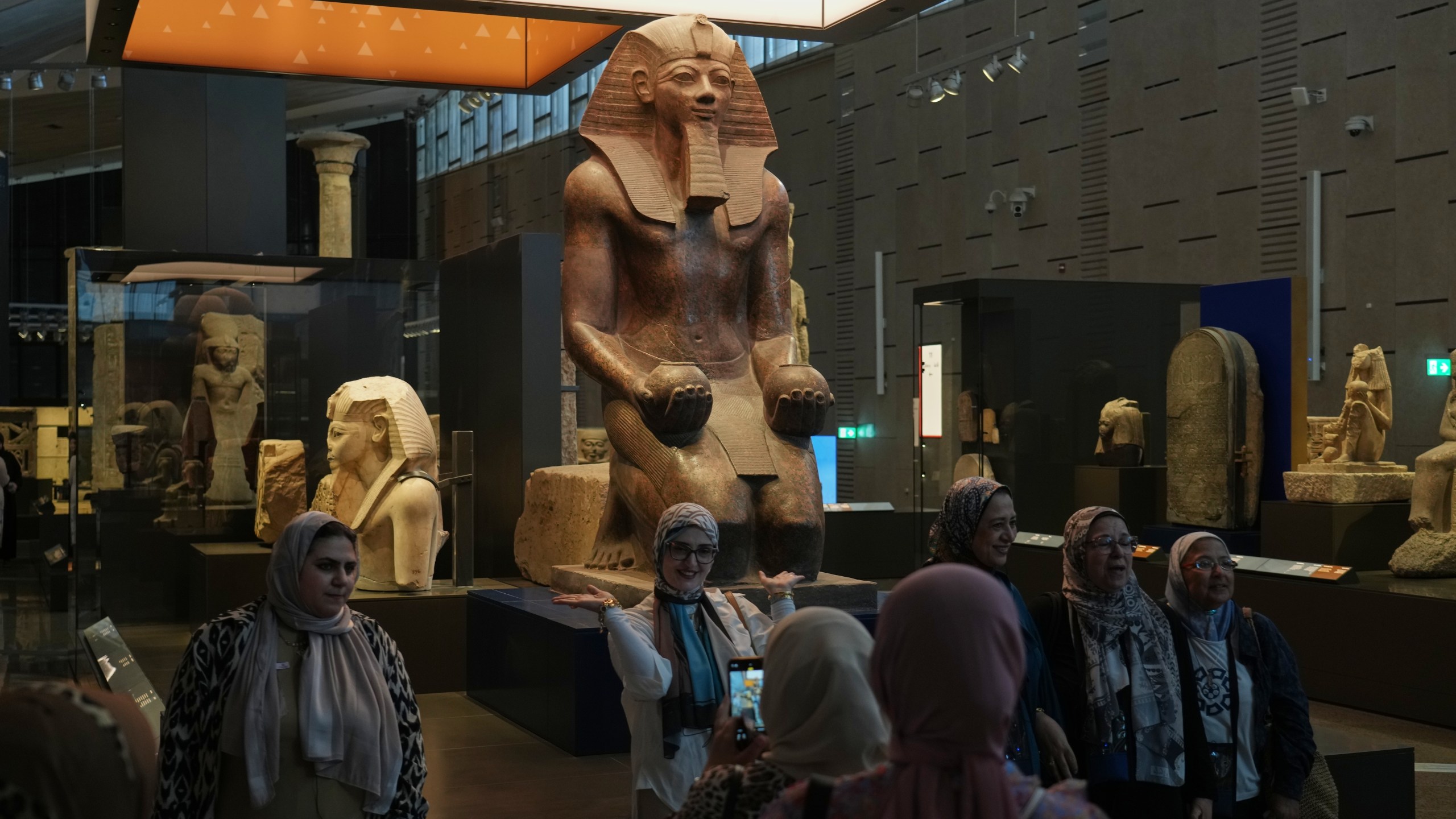 Visitors pose for a group photo under Hatshepsut statue, at the Grand Egyptian Museum in Giza, Egypt, Friday, May 23, 2025. (AP Photo/Amr Nabil)
