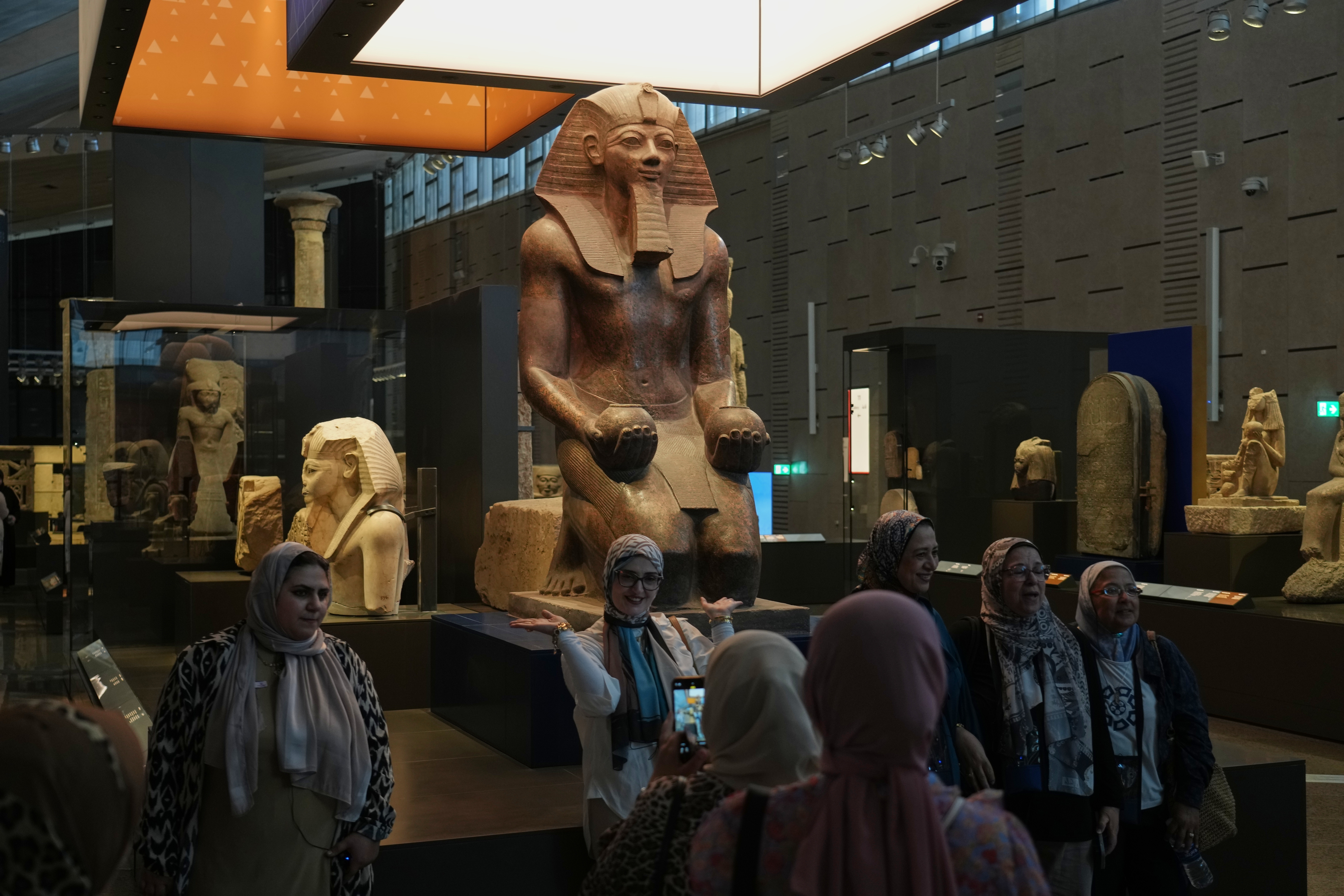 Visitors pose for a group photo under Hatshepsut statue, at the Grand Egyptian Museum in Giza, Egypt, Friday, May 23, 2025. (AP Photo/Amr Nabil)