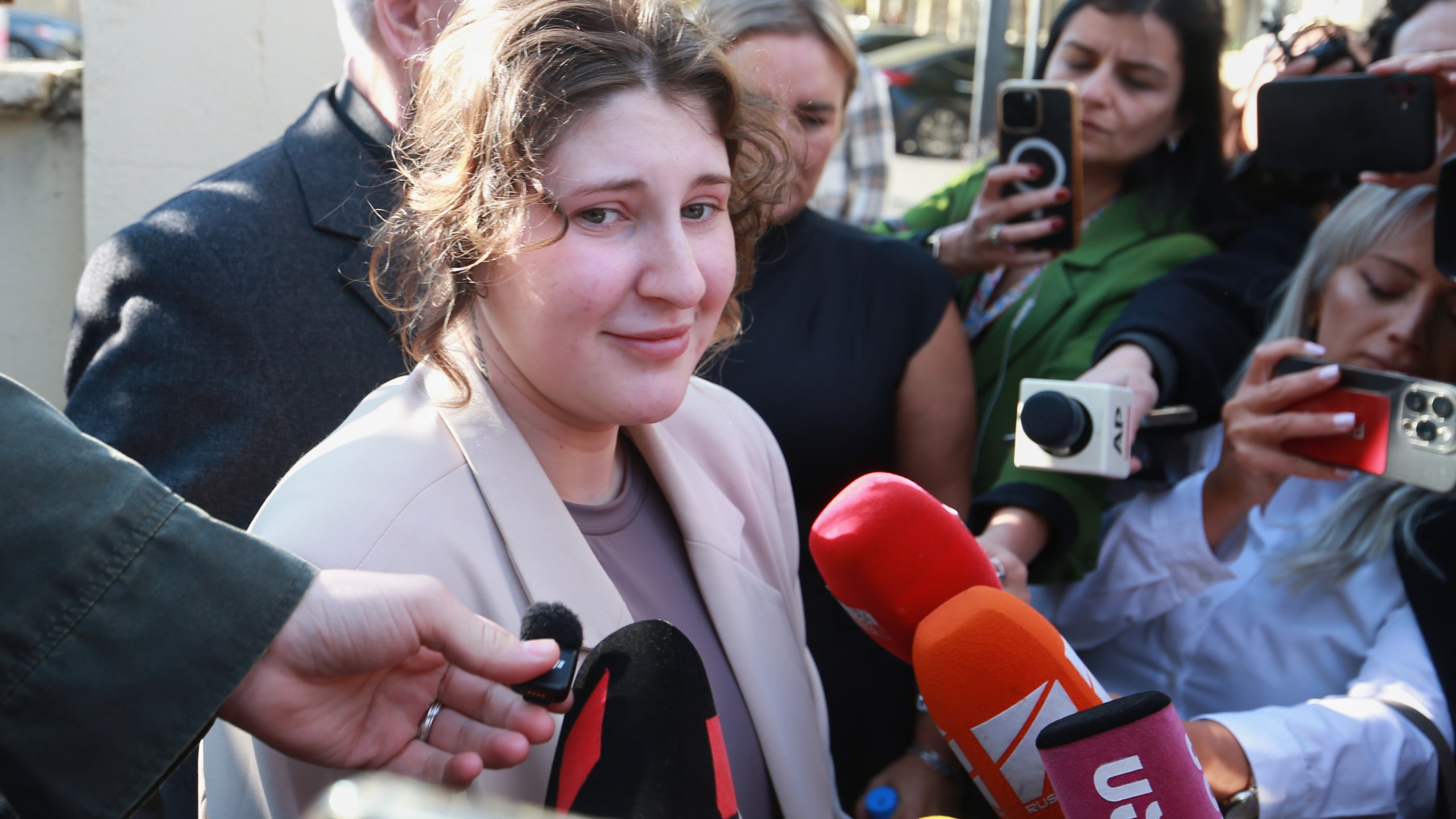 Bella May Culley, front left, 19-year-old, who was arrested upon arrival at the Tbilisi Airport in May and accused of attempting to smuggle marijuana and hashish into the country, speaks to journalists after she was released from prison near the court building in Tbilisi, Georgia, on Monday, Nov. 3, 2025, as her mother Lyanne Kennedy, stands behind. (AP Photo/Zurab Tsertsvadze)