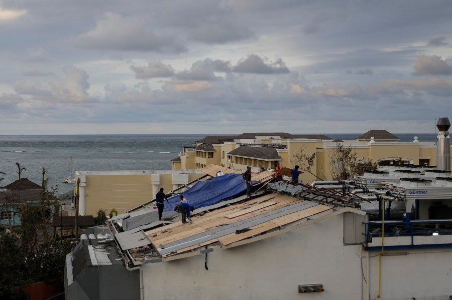 People repair the roof of a resort in Montego Bay, Jamaica, Friday, Oct. 31, 2025, in the aftermath of Hurricane Melissa. (AP Photo/Matias Delacroix)