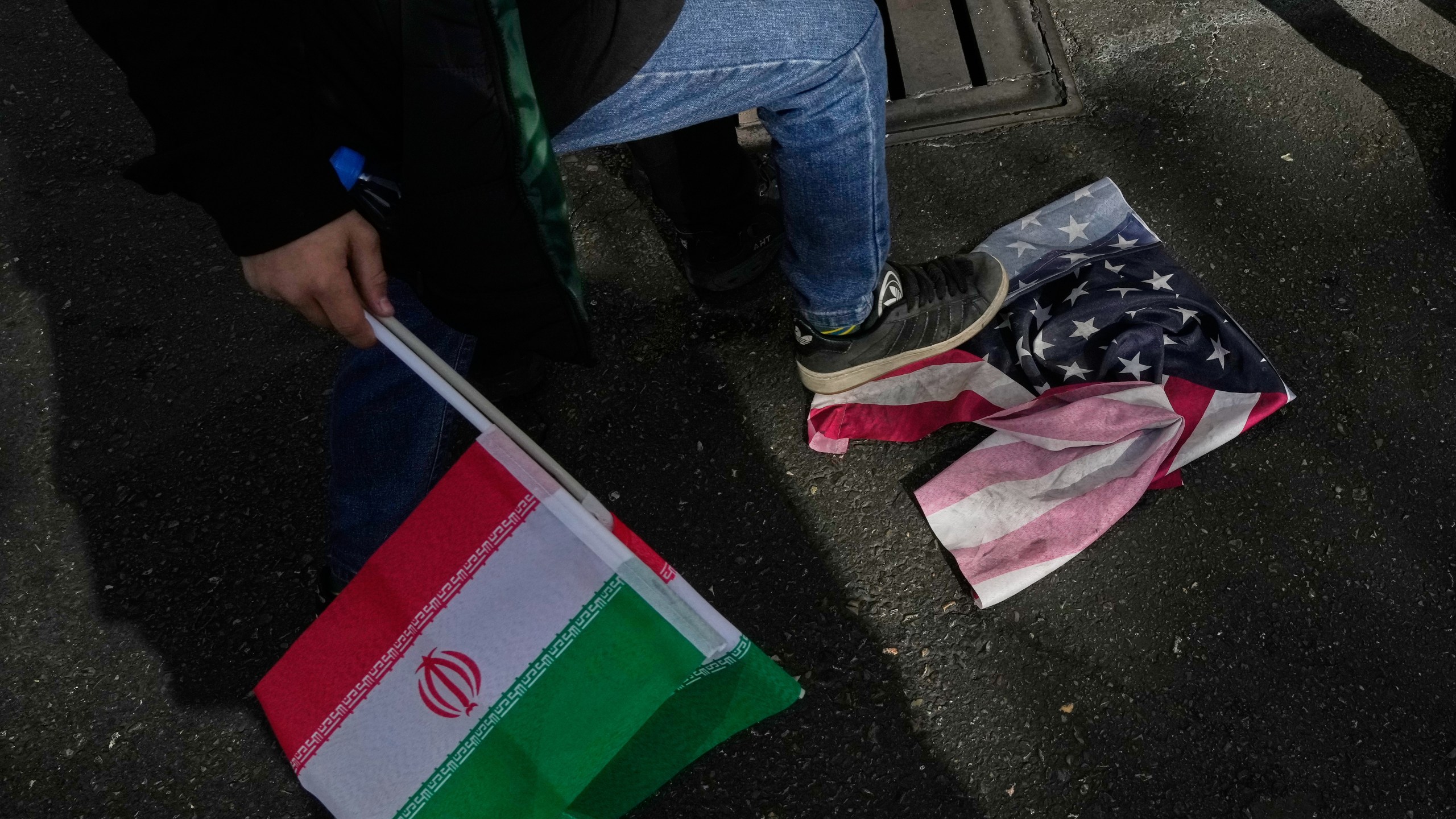 A school boy stomps a U.S. flag as he holds an Iranian flag during an annual rally in front of the former U.S. Embassy in Tehran, celebrating the anniversary of the 1979 takeover of the embassy, Iran, Tuesday, Nov. 4, 2025. (AP Photo/Vahid Salemi)