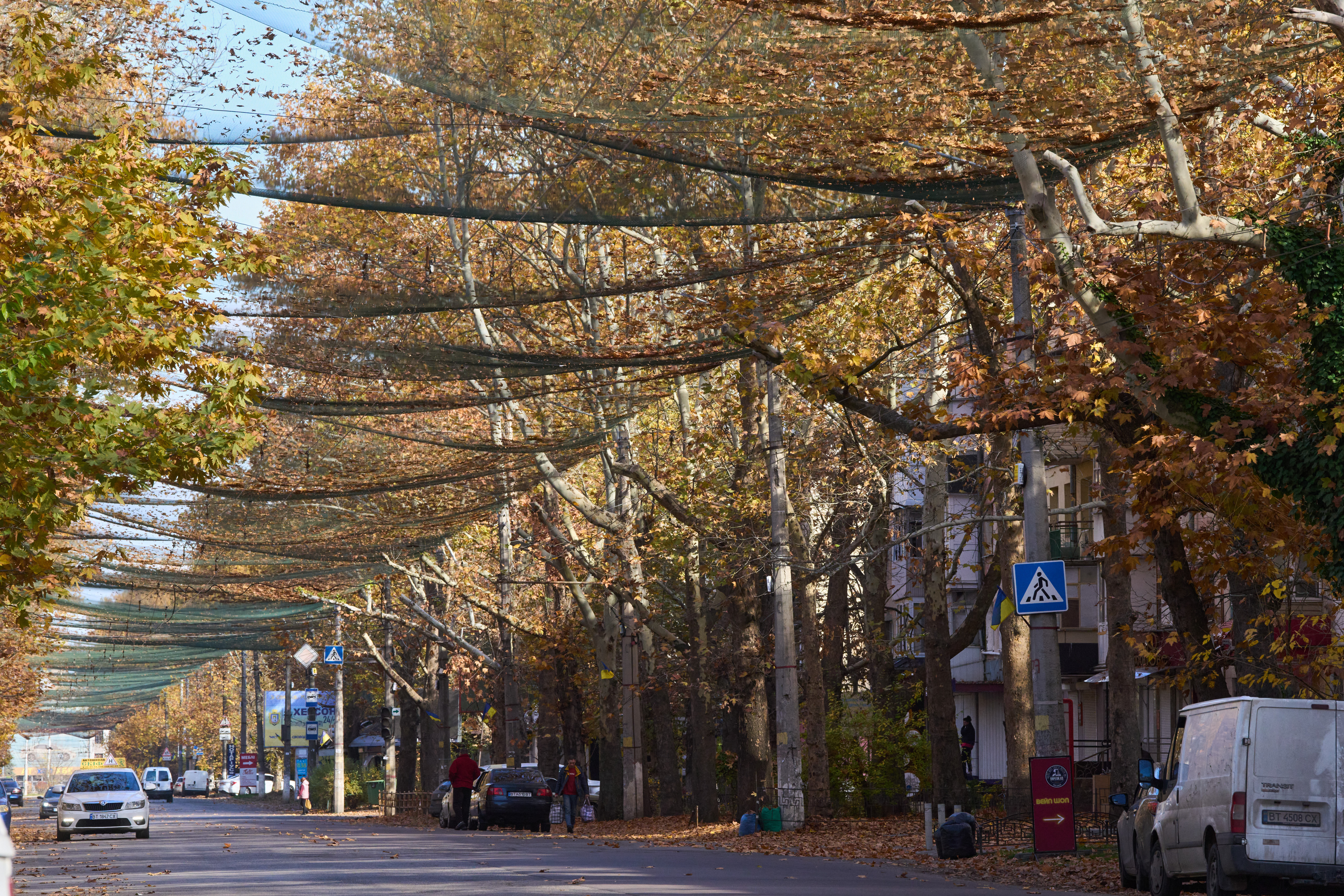 Local residents walk along the street covered with an anti-FPV-drone net in the frontline city of Kherson, Southern Ukraine, Monday, Nov. 3, 2025. (AP Photo/Efrem Lukatsky)