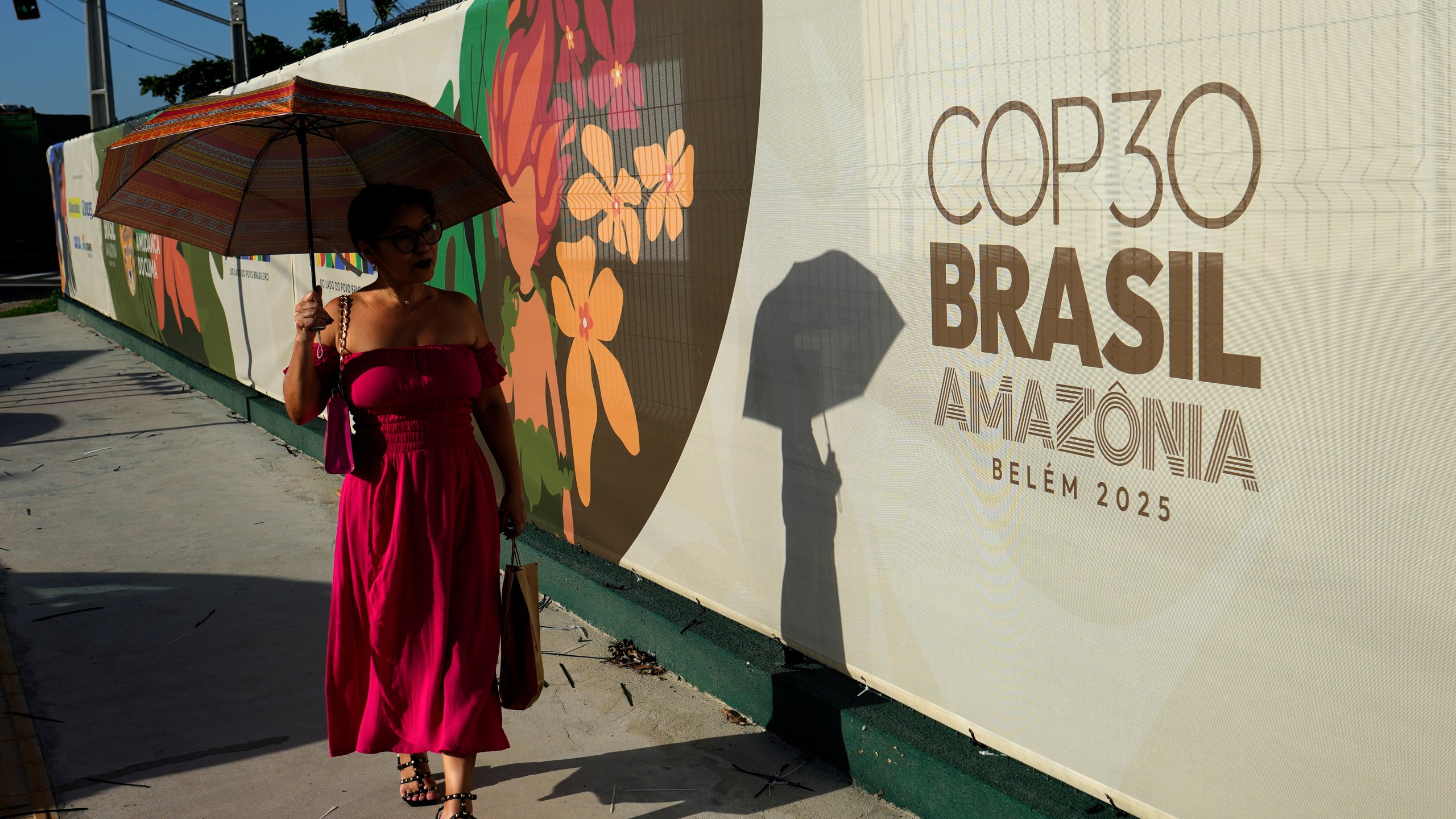 A woman walks past a sign for the COP30 U.N. Climate Summit, in Belem, Para state, Brazil, Tuesday, November 4, 2025. (AP Photo/Eraldo Peres)