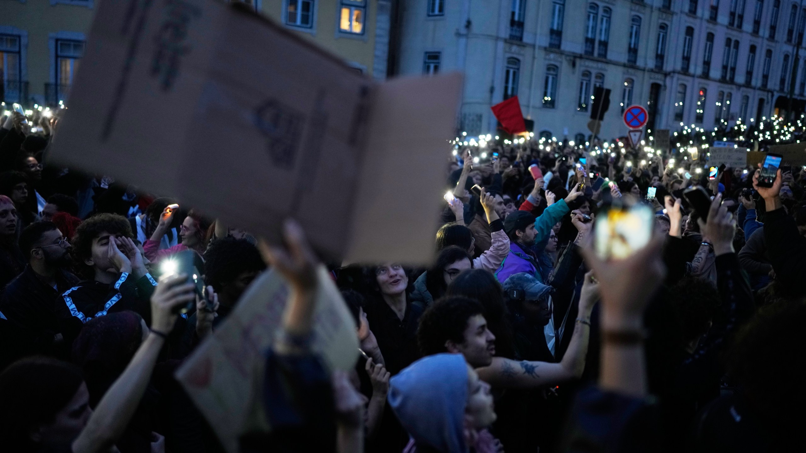 People hold up their cellphones outside the parliament in Lisbon during a general strike to protest against a new labour package announced by the centre-right government Thursday, Dec. 11, 2025. (AP Photo/Armando Franca)