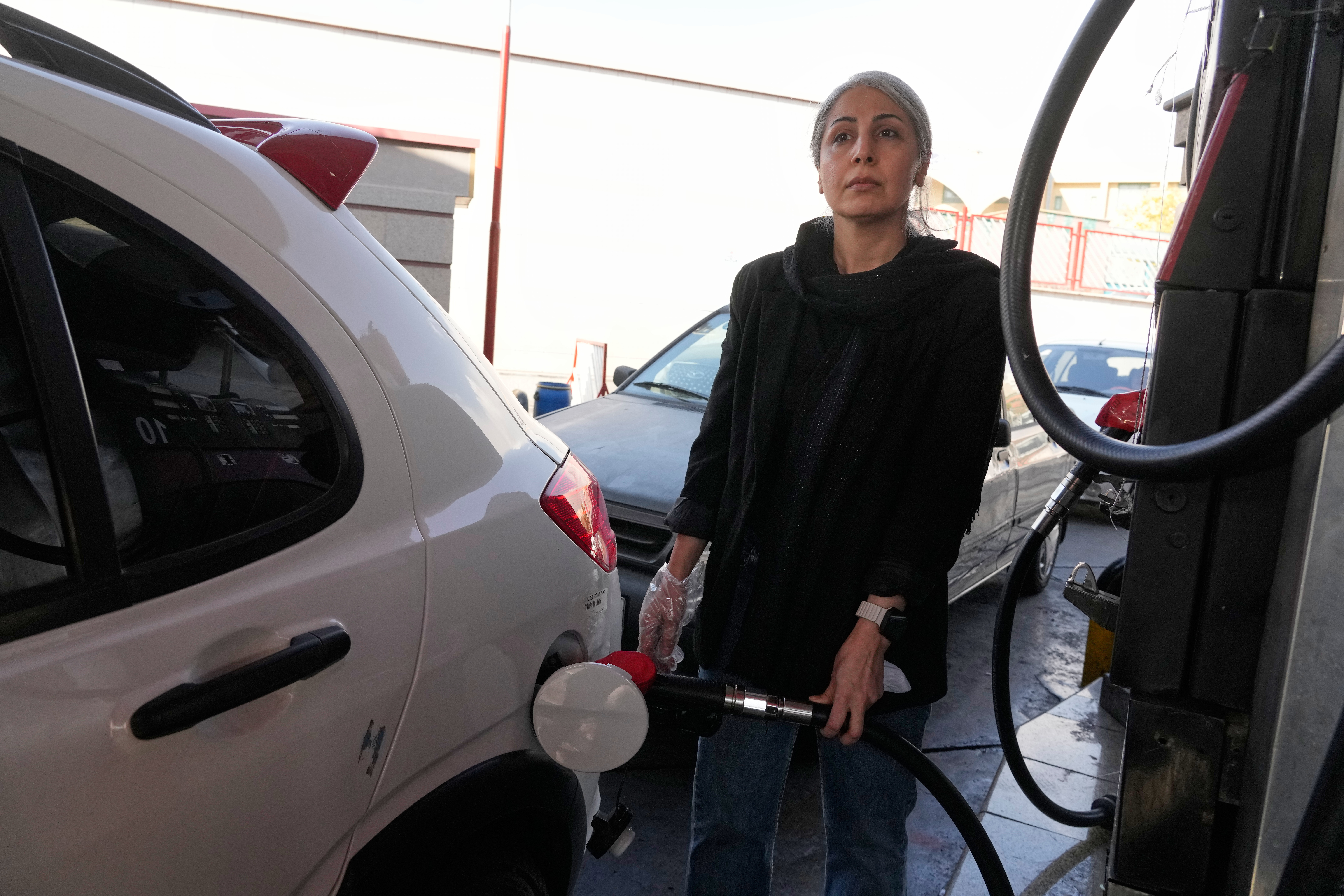 A woman fills her car at a gas station in Tehran, Iran, Thursday, Nov. 27, 2025. (AP Photo/Vahid Salemi)