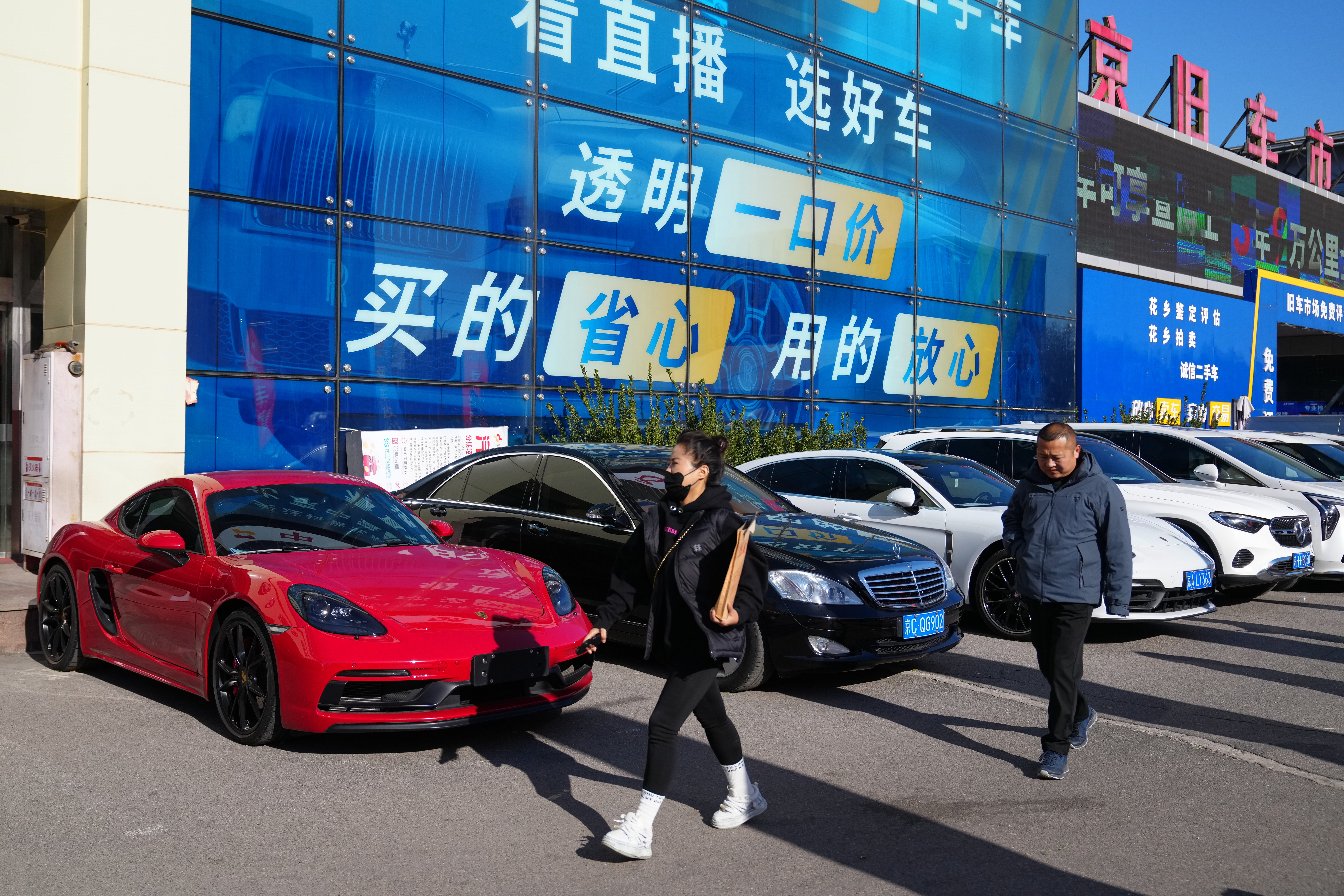People walk past a second hand market for luxury cars in Beijing, Tuesday, Nov. 25, 2025. (AP Photo/Andy Wong)