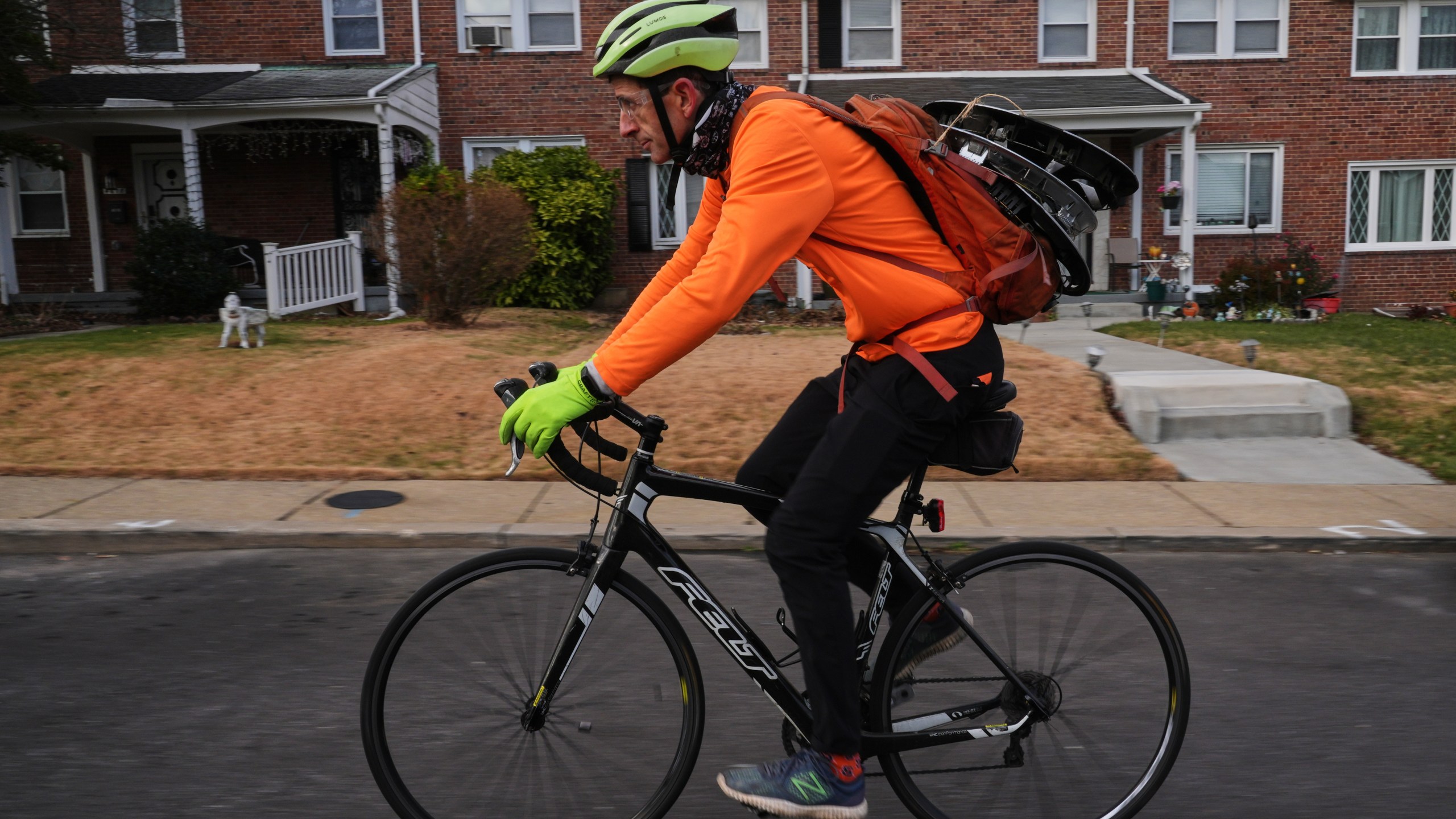 With hubcaps fastened to his backpack, cyclist Barnaby Wickham pedals through a neighborhood on his journey home, Thursday, Dec. 11, 2025, in Baltimore. (AP Photo/Stephanie Scarbrough)