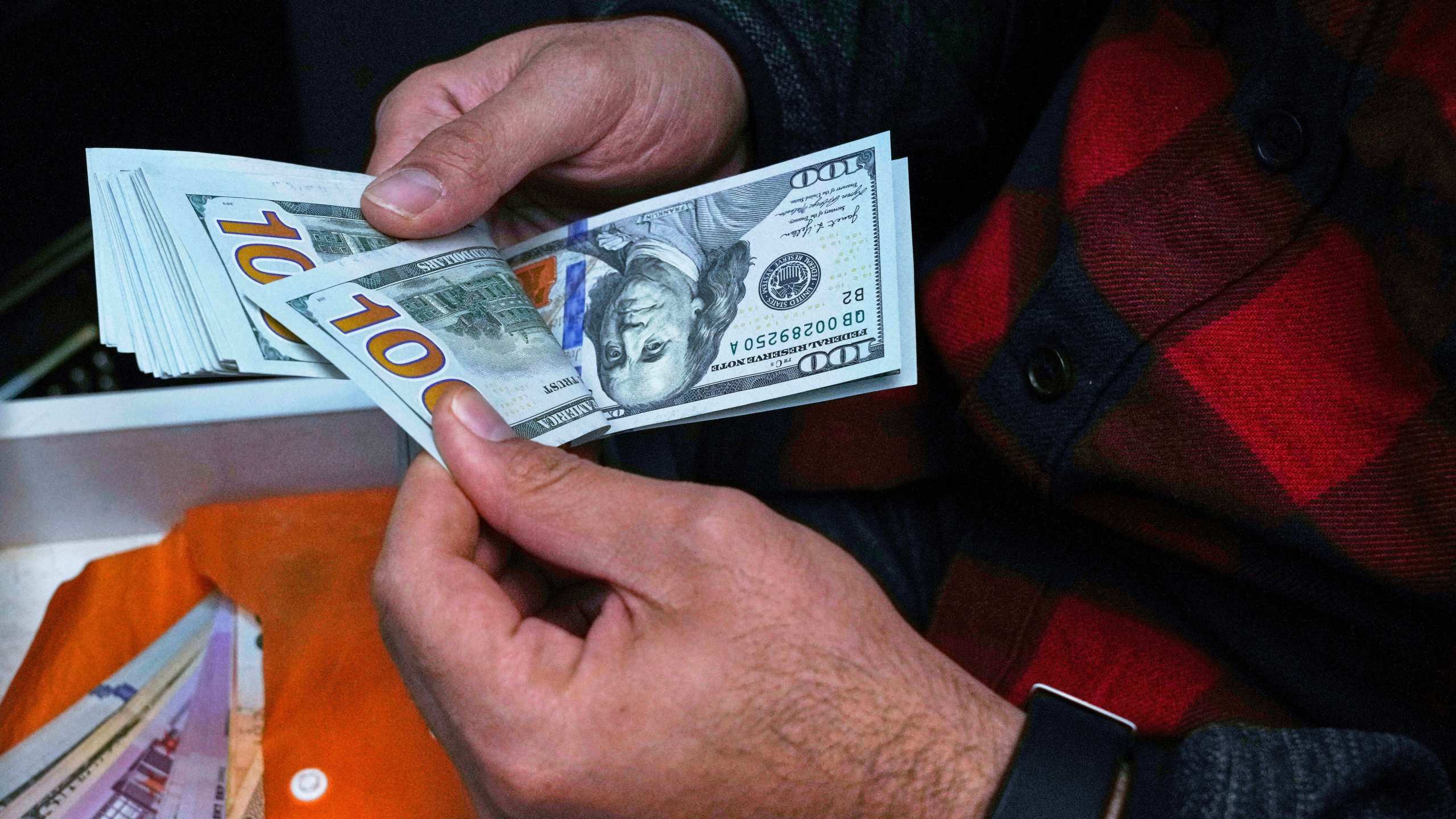 FILE — A currency exchange bureau worker counts U.S. dollars at Ferdowsi square, Tehran's go-to venue for foreign currency exchange, in downtown Tehran, Iran, April 5, 2025. (AP Photo/Vahid Salemi, File)