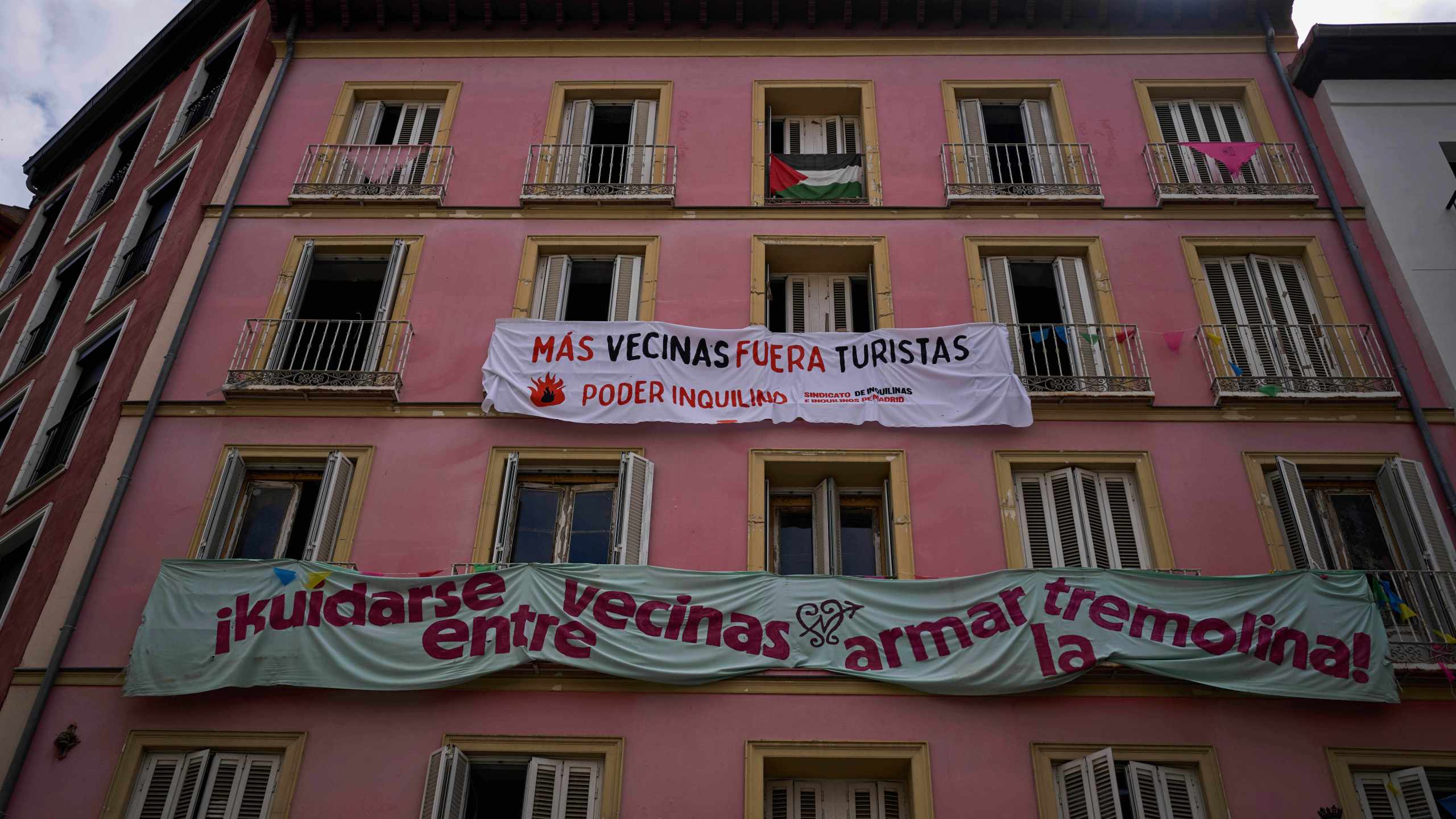 FILE - Banners against tourist holiday rentals hang on the facade of a building in downtown Madrid, Spain, Tuesday, June 3, 2025. The writing in Spanish reads: "More neighbors, fewer tourists. Tenant power," and "Looking out for each other as neighbors, stirring things up." (AP Photo/Manu Fernandez)
