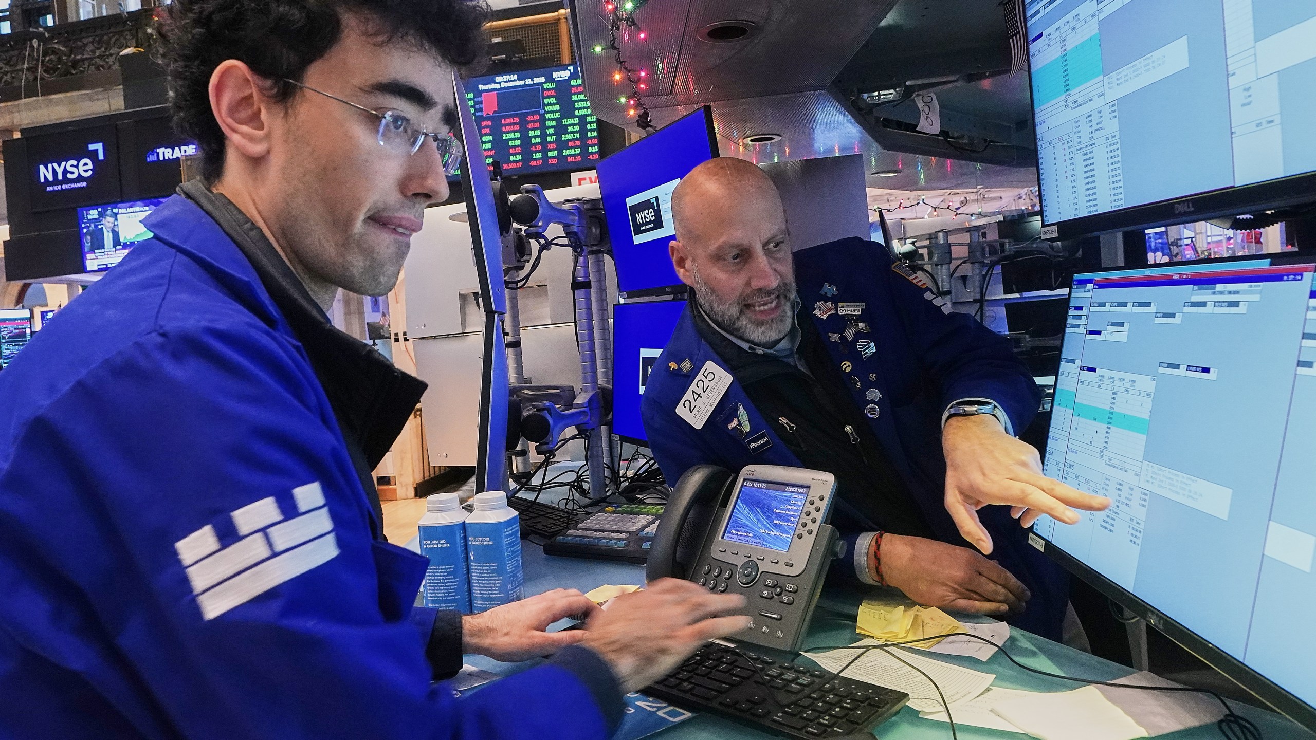 Specialists Alex Weitzman, left, and Meric Greenbaum work on the floor of the New York Stock Exchange, Thursday, Dec. 11, 2025. (AP Photo/Richard Drew)