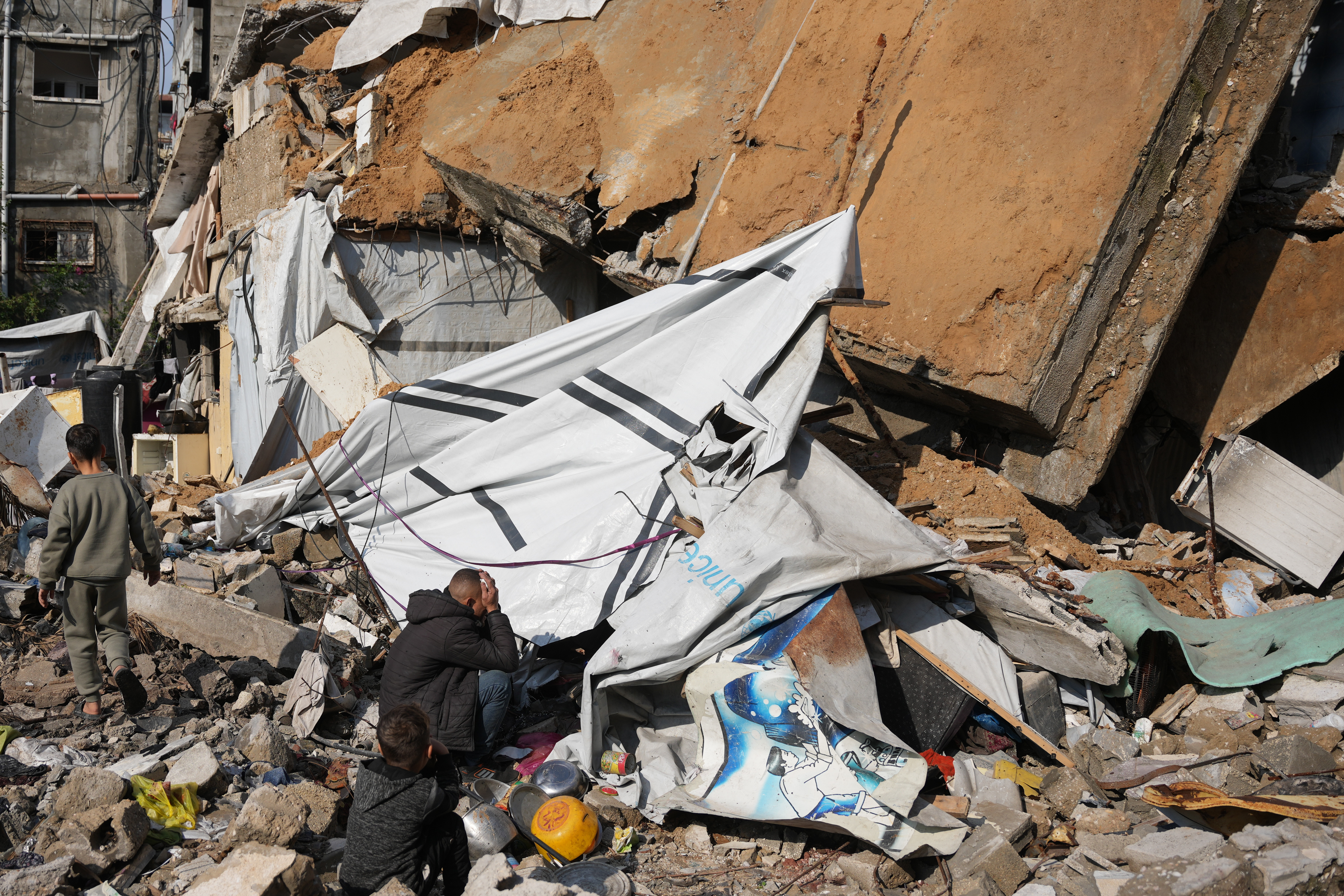 Alaa al-Hosari sits on the rubble of his house that collapsed, killing, according to Al-Shafa Hospital officials, at least one person and leaving several others injured in Gaza City, Tuesday, Dec. 16, 2025. (AP Photo/Abdel Kareem Hana)
