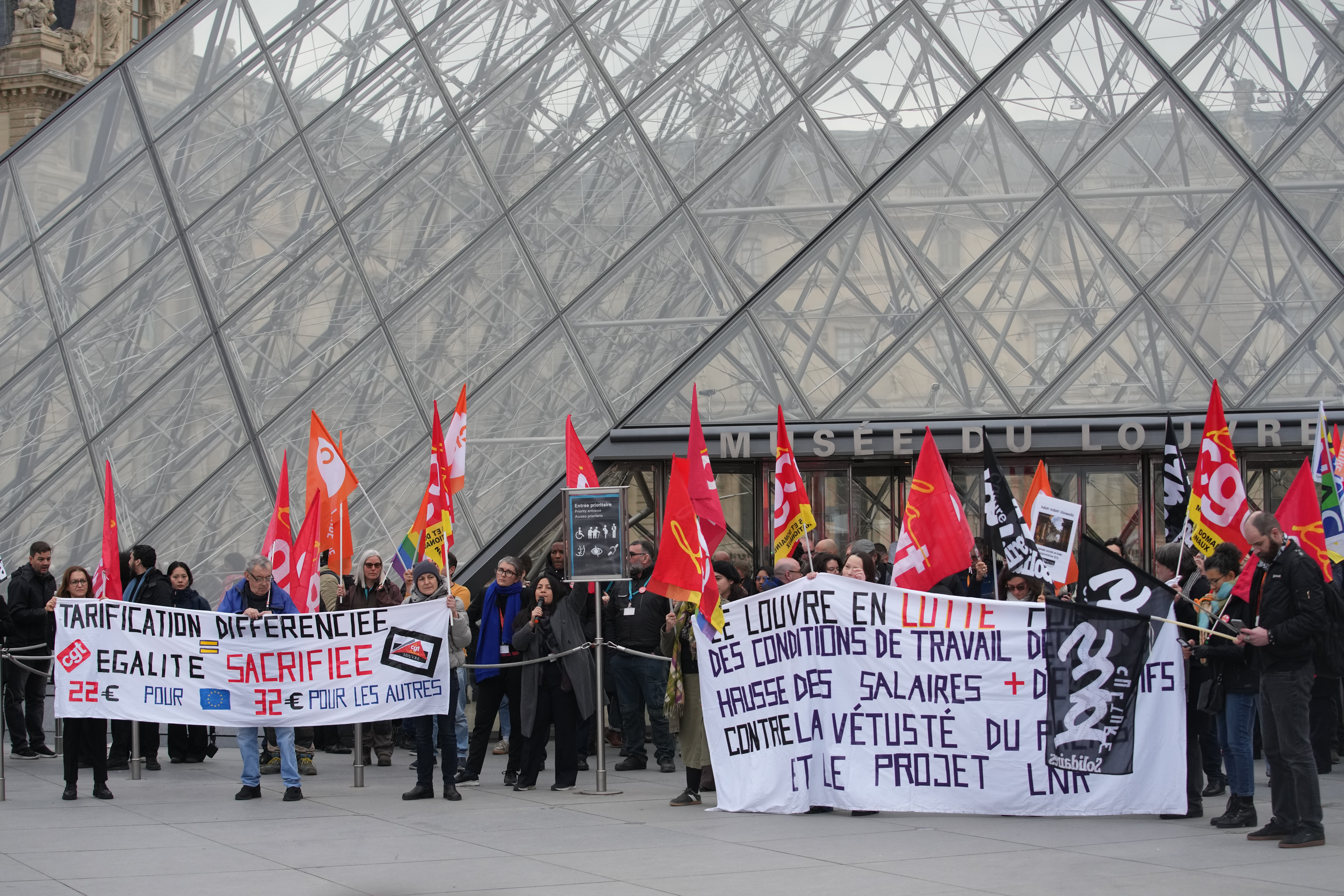 Unionists display a banner and union flags outside the Louvre museum after employees have voted to extend a strike that has disrupted operations at the world's most visited museum, Wednesday, Dec. 17, 2025 in Paris. (AP Photo/Christophe Ena)