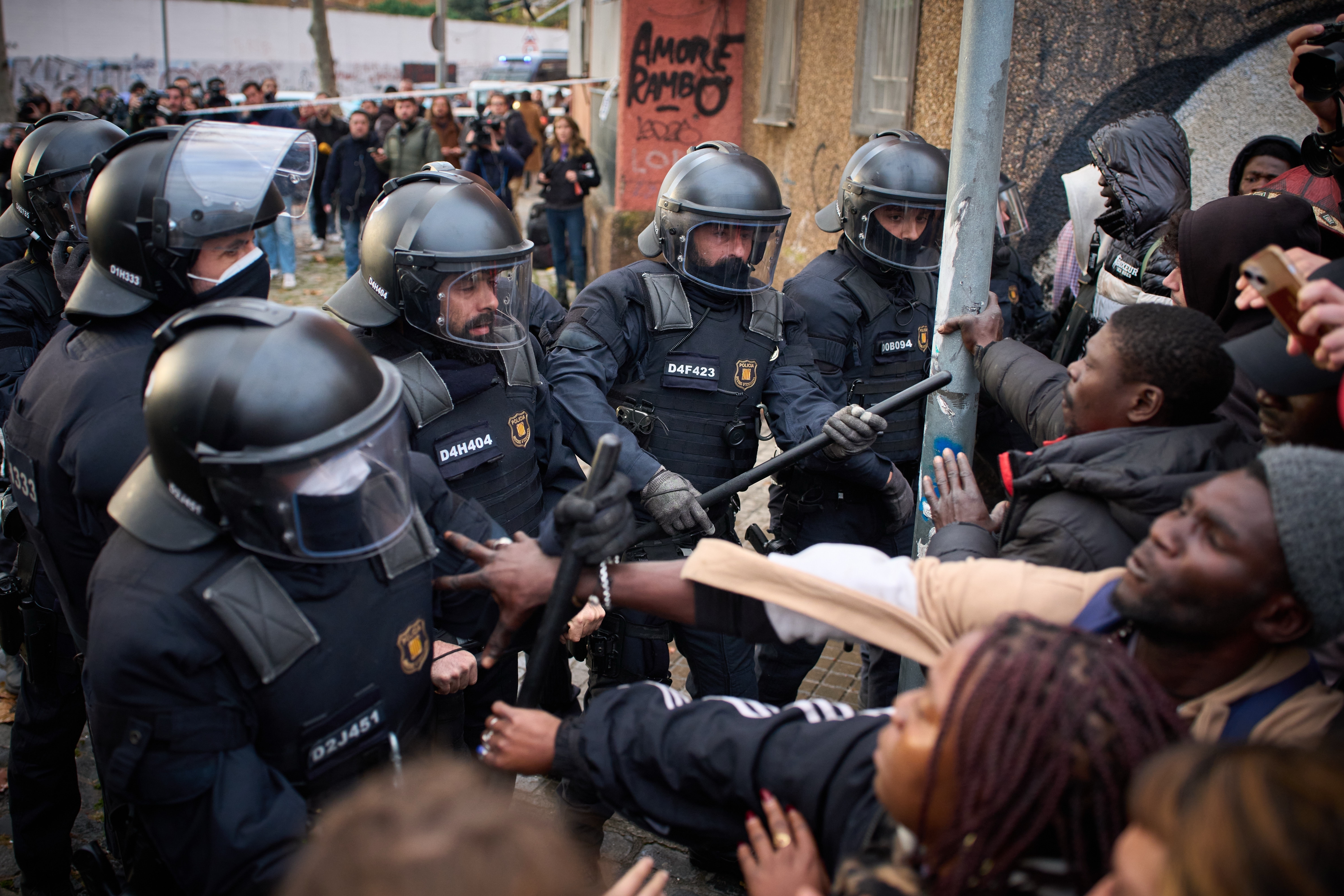 Migrants confront police as they begin carrying out eviction orders at an abandoned school building where hundreds of mostly undocumented migrants had been living, in Badalona, near Barcelona, Spain, Wednesday, Dec. 17, 2025. (AP Photo/Emilio Morenatti)