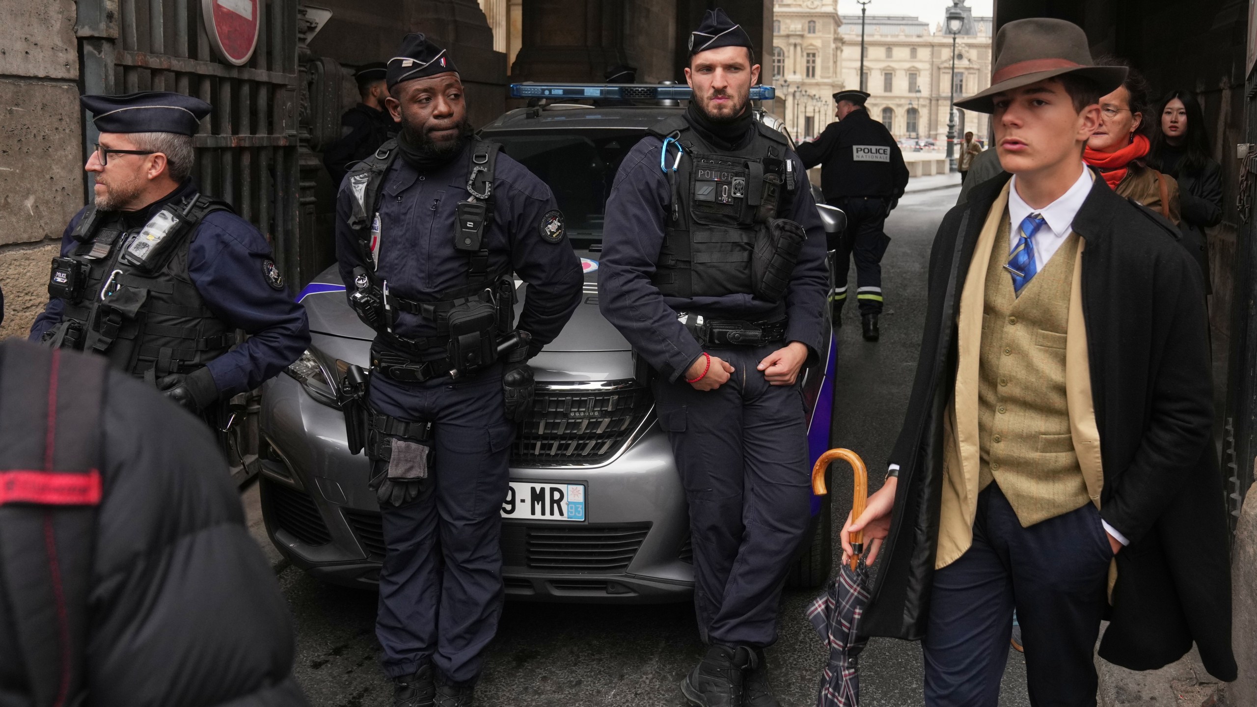 FILE - Pedro Elias Garzon Delvaux, right, walks past as police officers block an entrance to the Louvre after thieves carried out a daylight raid on French crown jewels, in Paris, Oct. 19, 2025. (AP Photo/Thibault Camus, File)