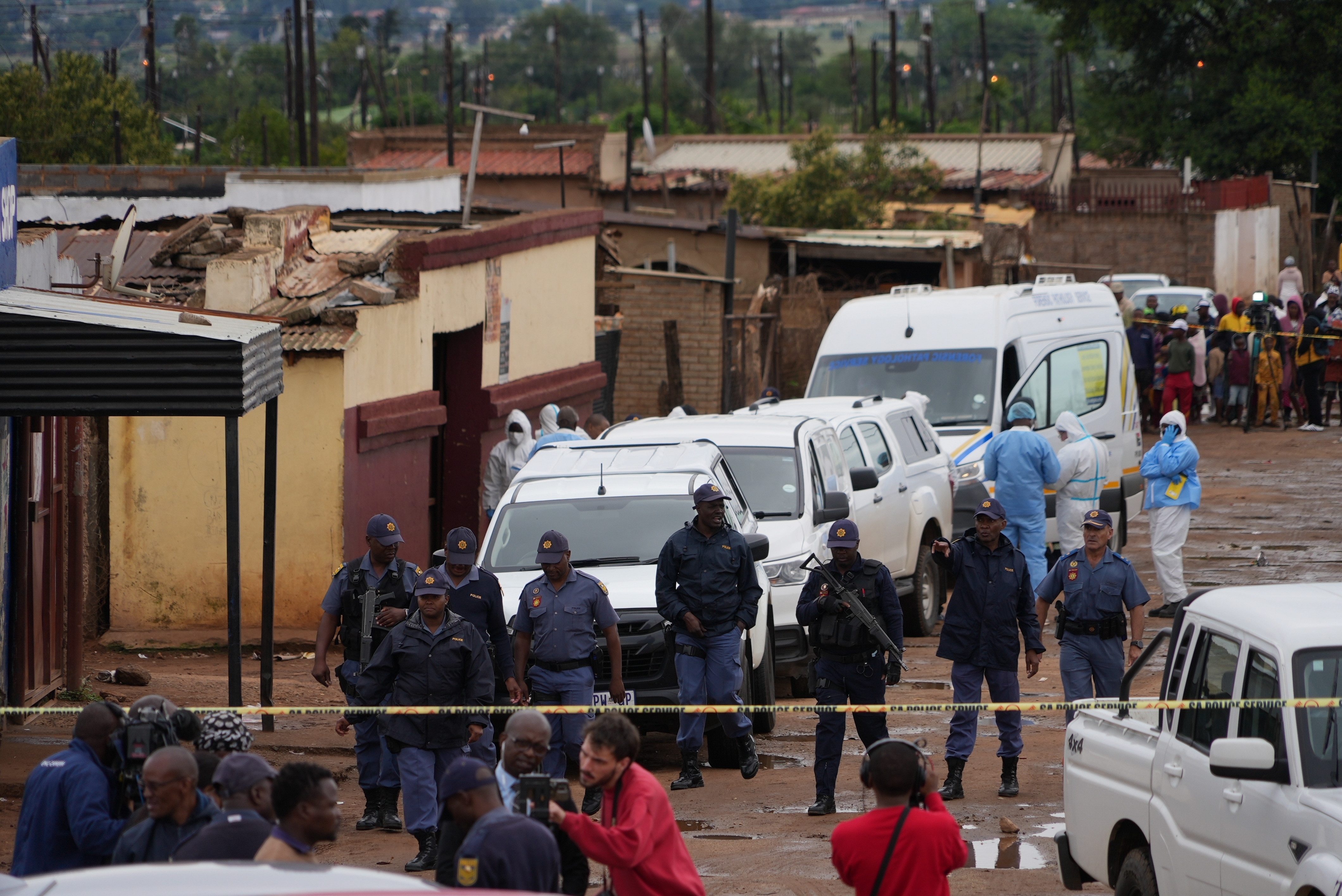 South African police gather at the scene of a mass shooting where gunmen killed nine and injured at least 10 in a pub in Bekkersdal, South Africa, Sunday, Dec. 21, 2025. (AP Photo/ Alfonso Nqunjana)