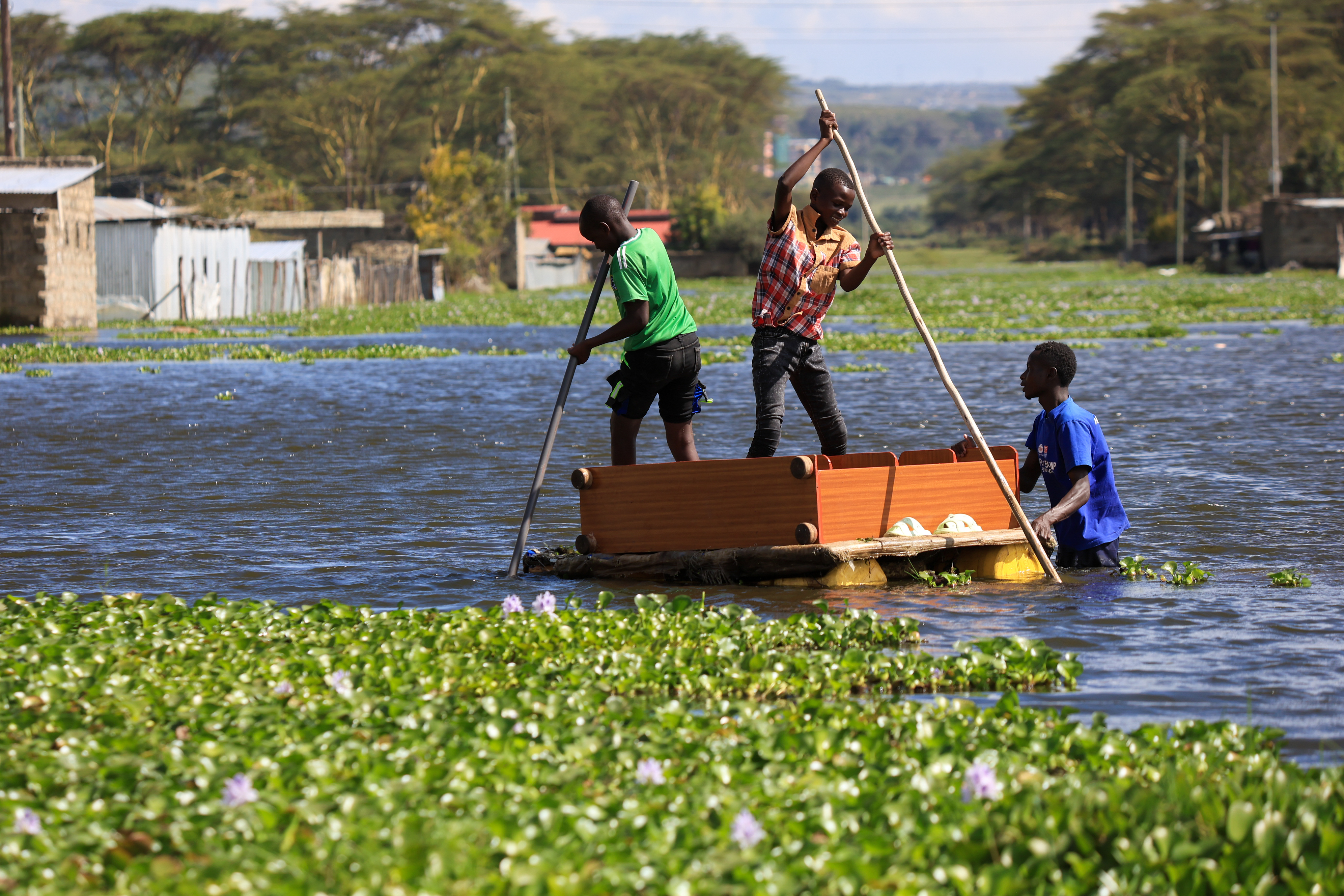 People use a boat to cross floodwaters as residential buildings remain submerged after Lake Naivasha swelled and inundated homes, displacing people in Kihoto Village, in Naivasha, Kenya's Rift Valley region, on Tuesday, Nov. 11, 2025. (AP Photo/Andrew Kasuku)