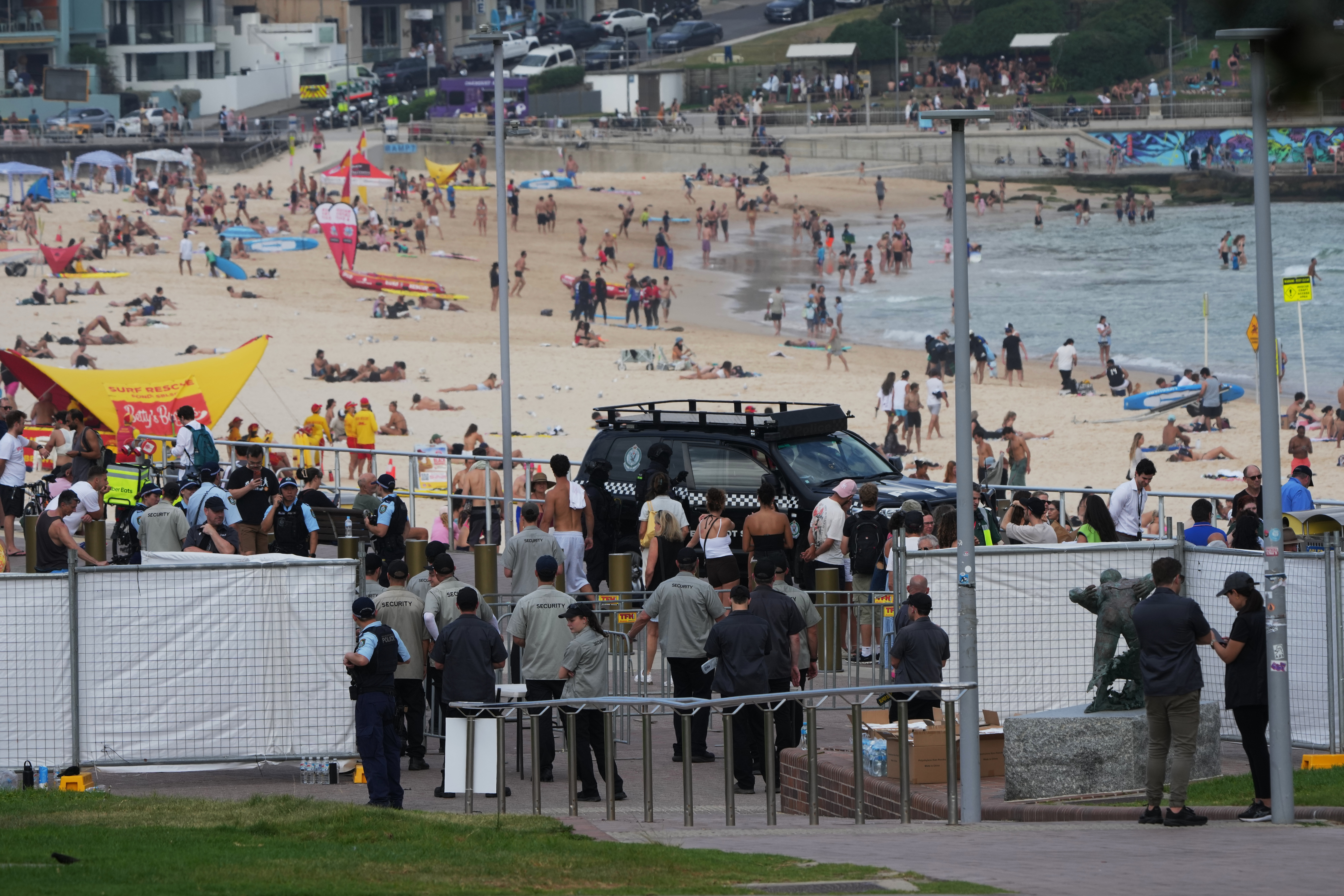 Security officers gather near a gate at Bondi Beach in Sydney, Sunday, Dec. 21, 2025, ahead of a ceremony to mark the National Day of Reflection for victims and survivors from the Bondi shooting on Dec. 14. (AP Photo/Mark Baker)