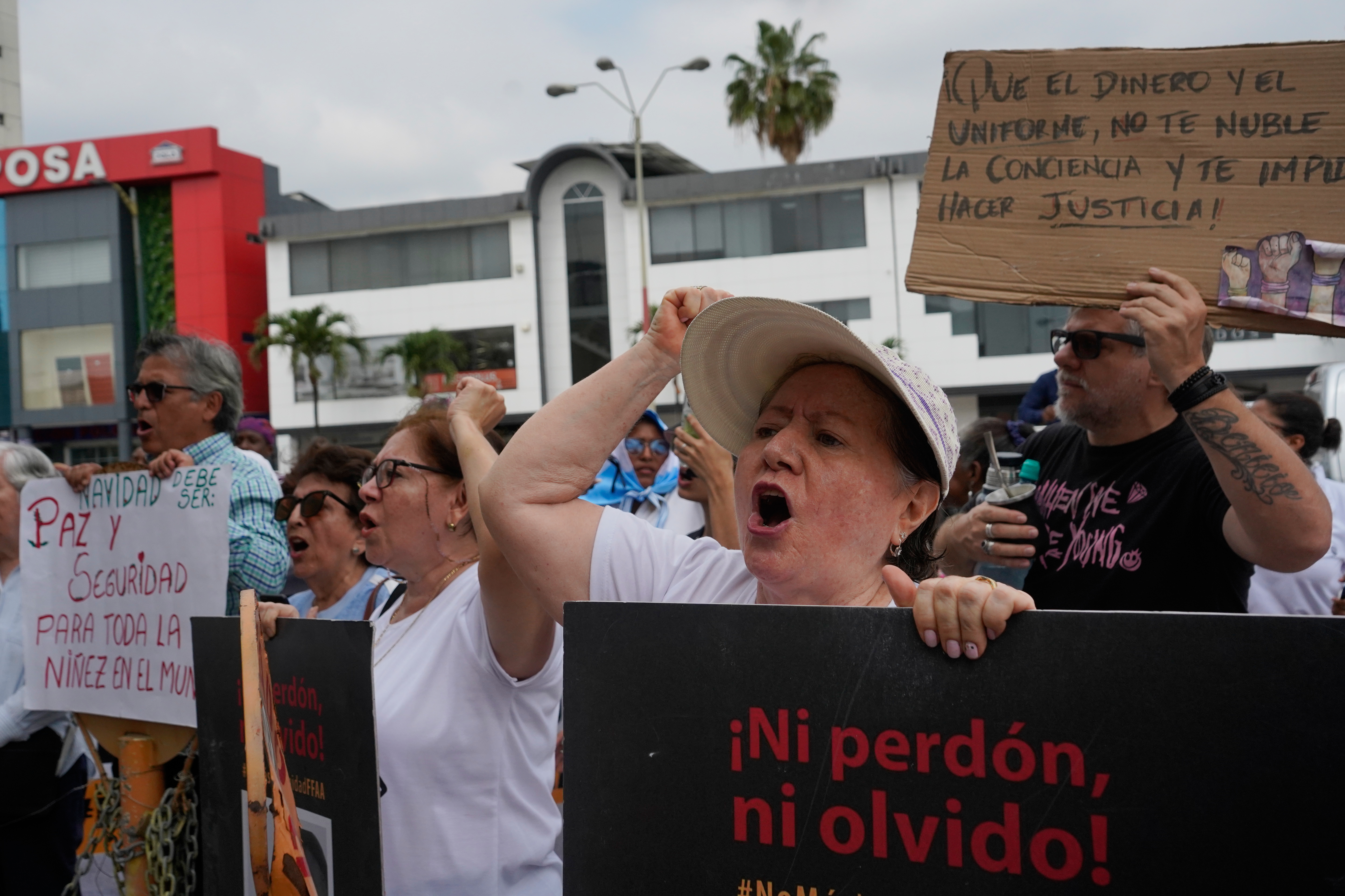 Protesters hold banners outside the courthouse where soldiers were sentenced for the disappearance and killing of four children who went missing in December 2024, in Guayaquil, Ecuador, Monday, Dec. 22, 2025. (AP Photo/Cesar Munoz)