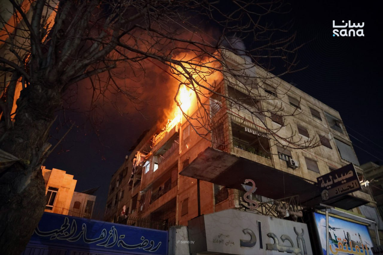 This photo released by the official Syrian news agency SANA, shows flames rising from a building after clashes broke out between security forces and Kurdish fighters in neighborhoods of the northern Syrian city of Aleppo, Syria, Monday, Dec. 22, 2025. (SANA via AP)