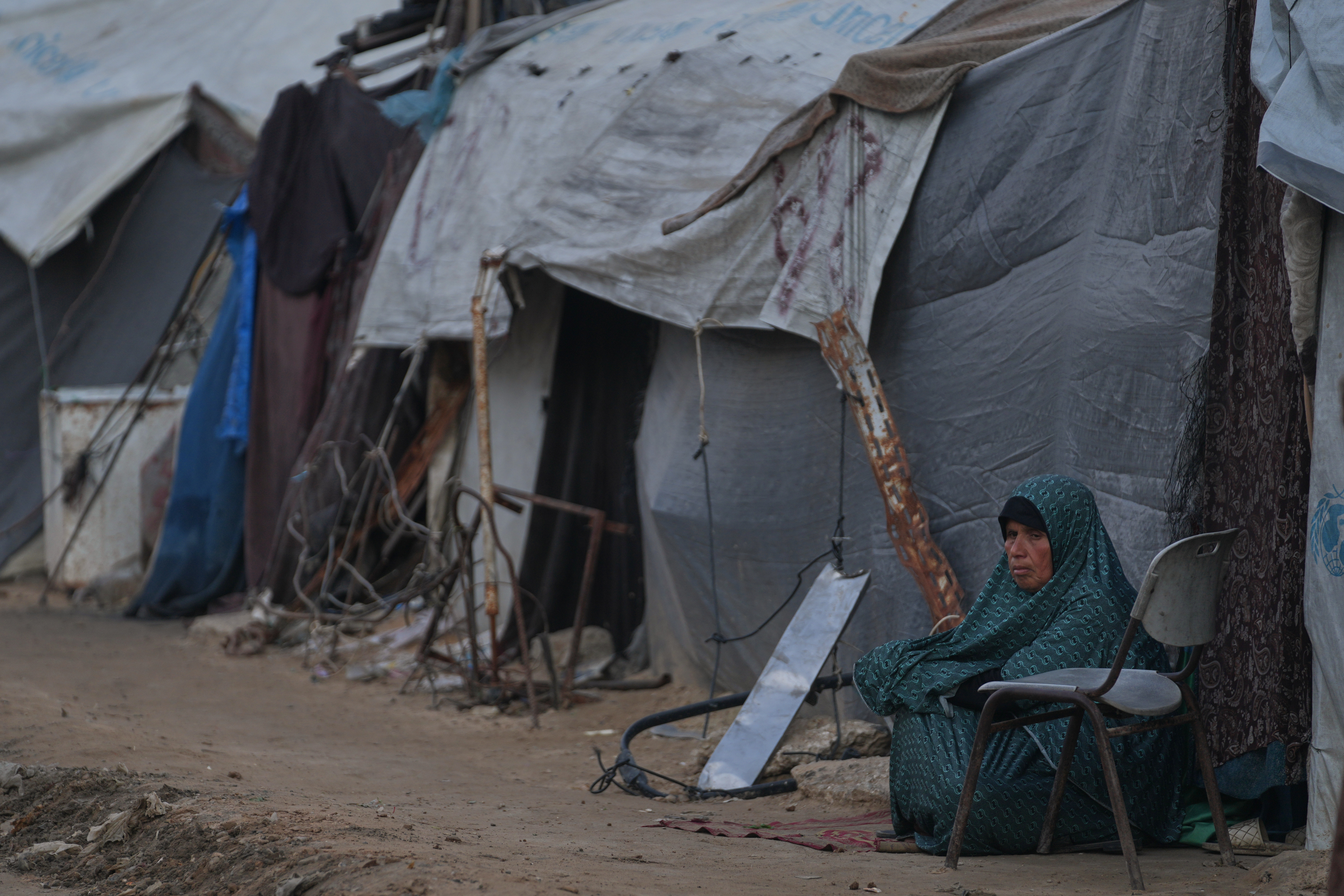 A woman sits next to her tent on an alley of a makeshift tent camp for displaced Palestinians in Deir al-Balah, central Gaza Strip, Tuesday, Dec. 23, 2025. (AP Photo/Abdel Kareem Hana)