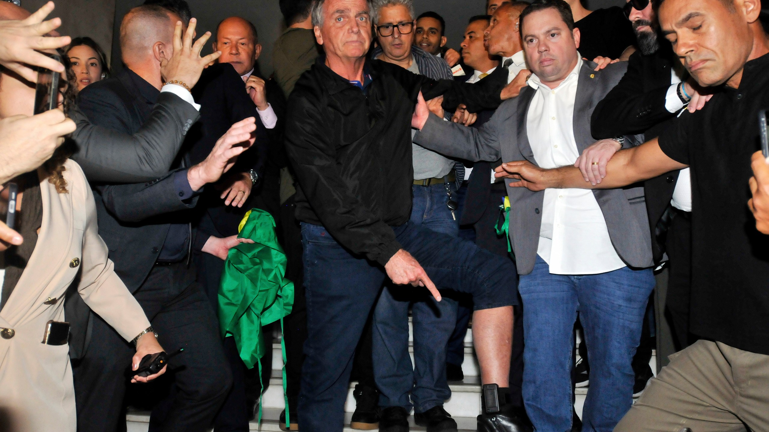 Brazil's former President Jair Bolsonaro points to his electronic ankle monitor that the Supreme Court ordered him to wear, at Congress in Brasilia, Brazil, July 21, 2025. (AP Photo/Minervino Junior, CB/D.A Press, File)