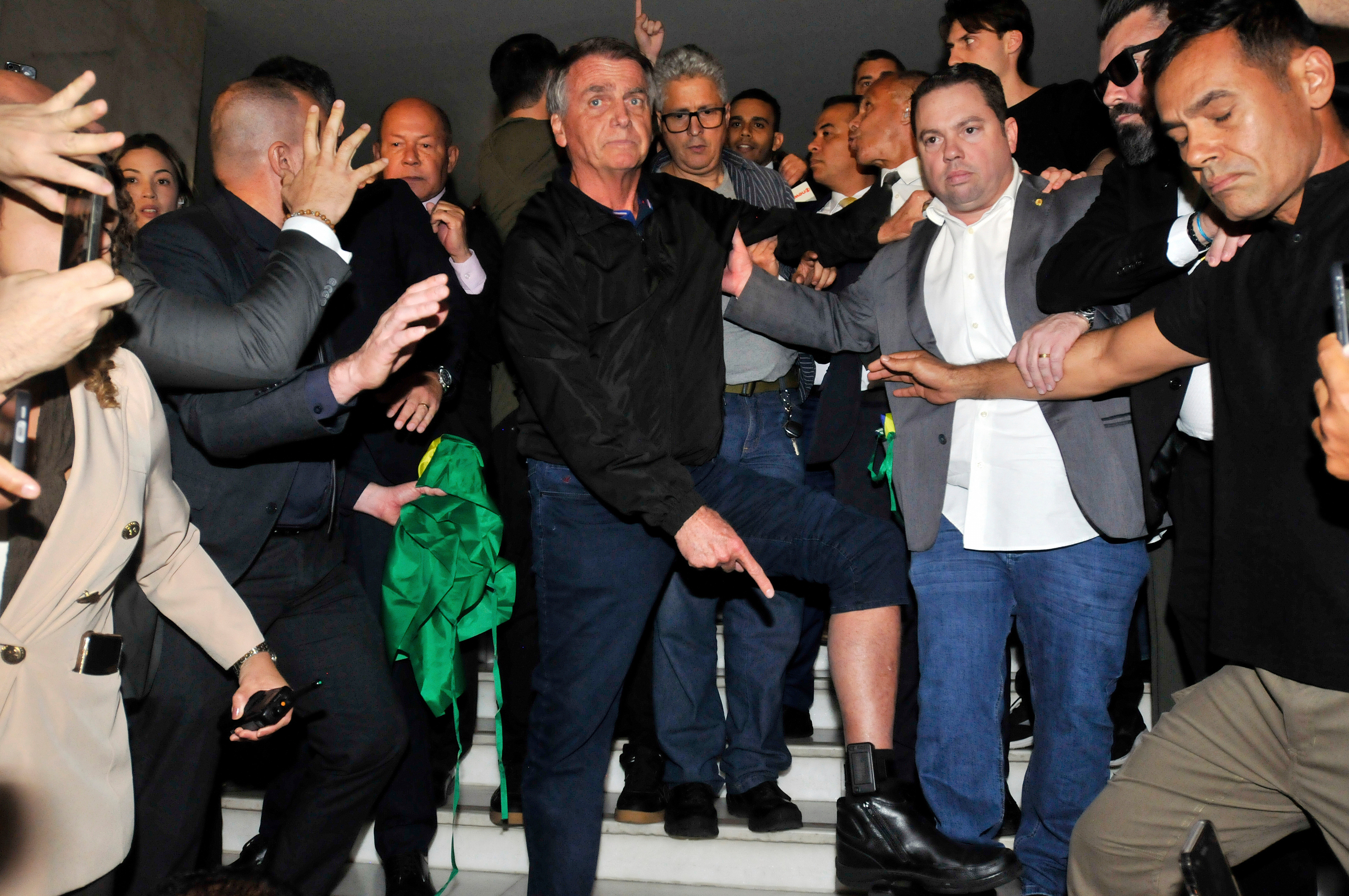 Brazil's former President Jair Bolsonaro points to his electronic ankle monitor that the Supreme Court ordered him to wear, at Congress in Brasilia, Brazil, July 21, 2025. (AP Photo/Minervino Junior, CB/D.A Press, File)